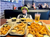 A boy seated at a restaurant with a variety of food on the table. 