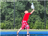 A boy playing tennis on a rainy court. 