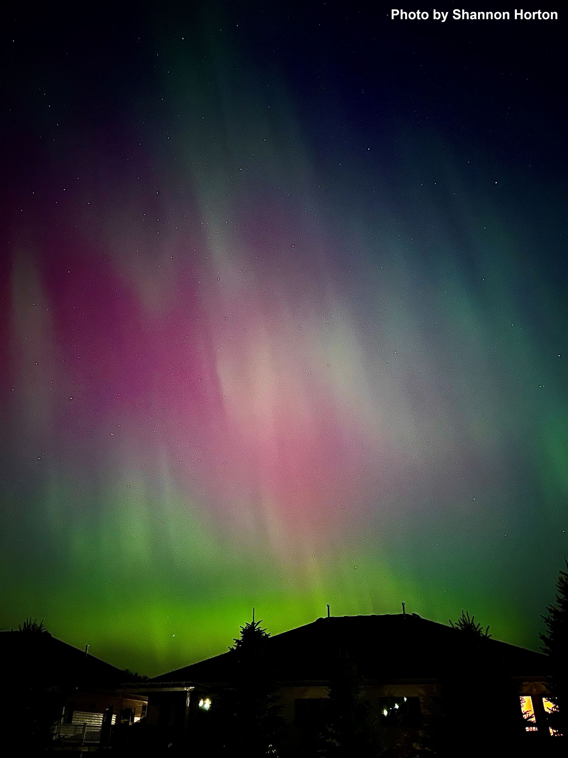 Northern Lights in the sky behind a house. 