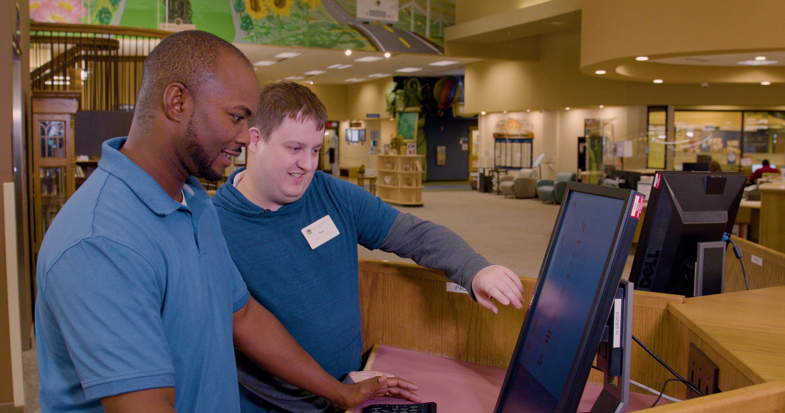 Library staff assisting a man at a computer