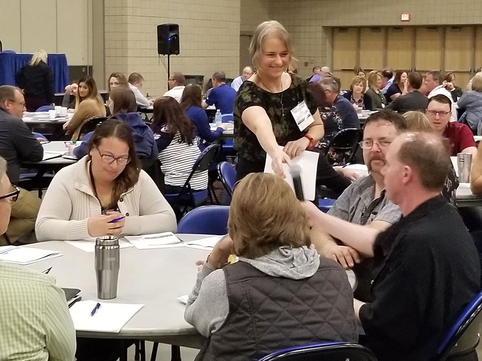 Woman handing microphone to HPAC member during tabletop exercise. 